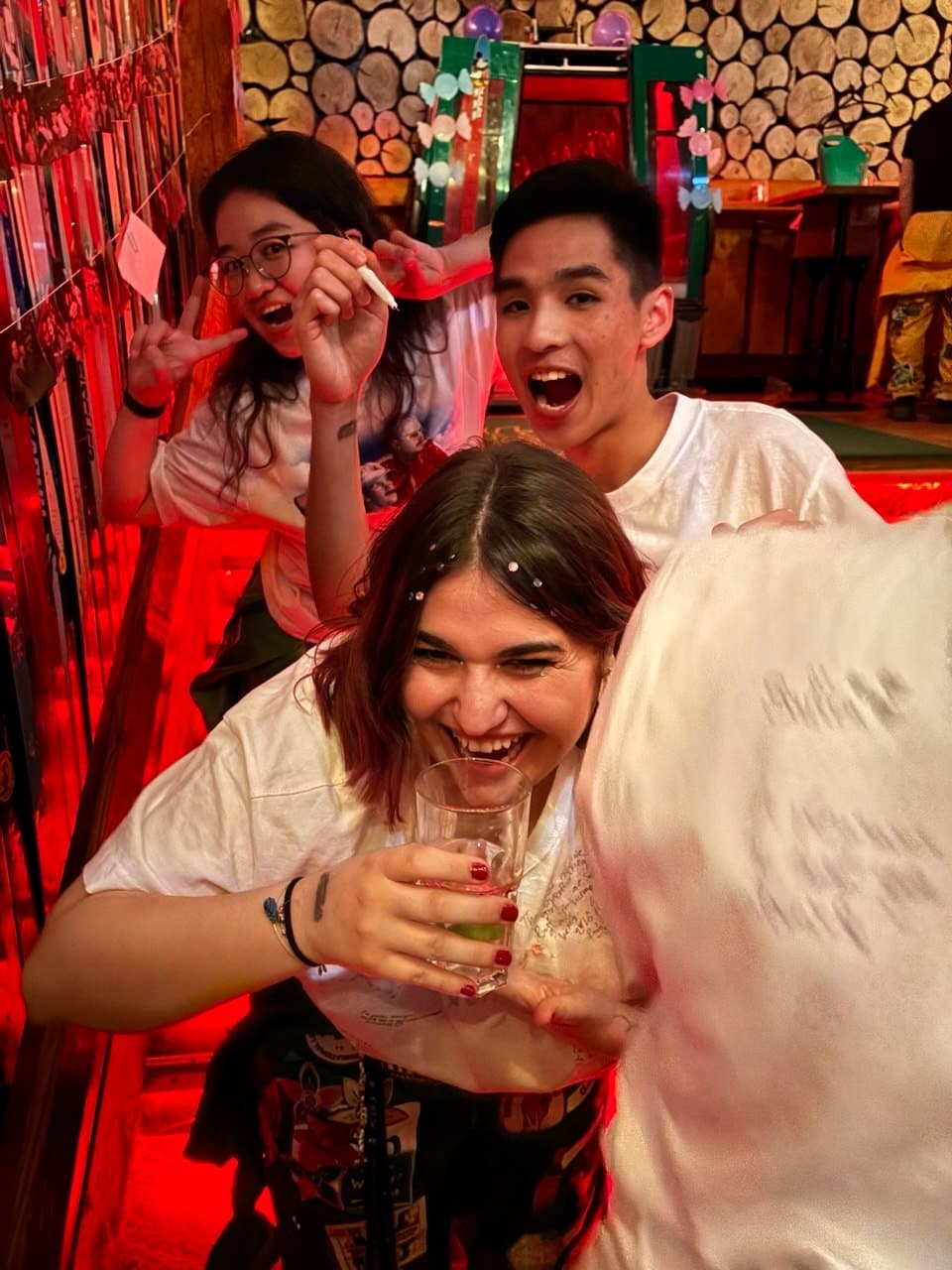 Three students laughing on the stairs of a student bar
