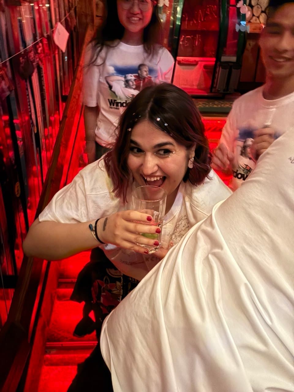 Student smiling with a drink under red club lighting